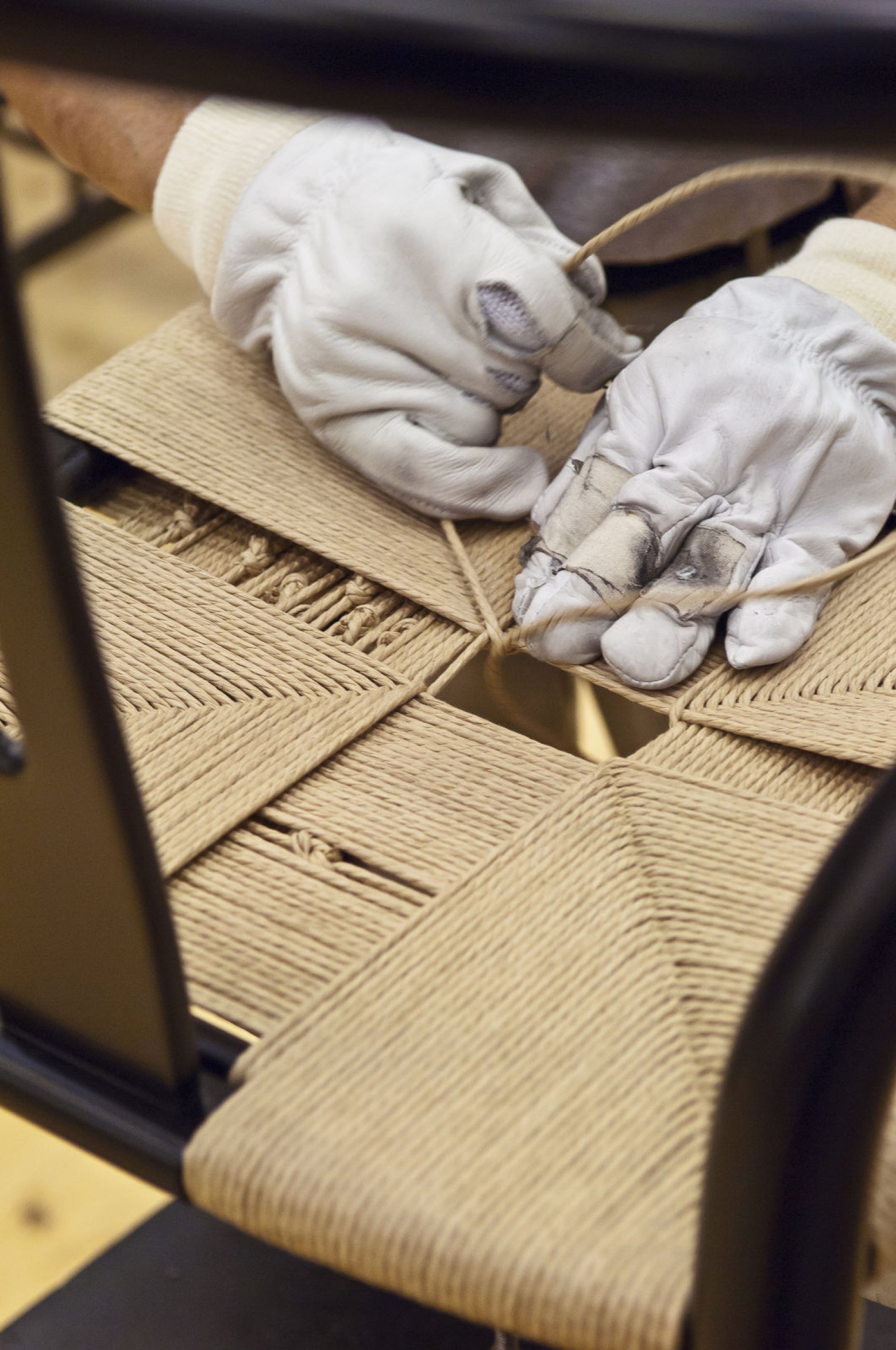De hand gewoven zitting van de iconische CH24 stoel vereist vakmanschap  Victors Design Agency